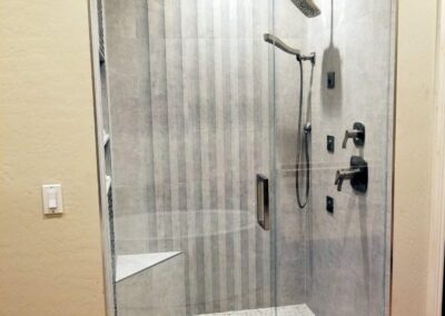 “Frameless glass shower with a swinging door and fixed side panel installed by A Cut Above Glass in Scottsdale, AZ.”